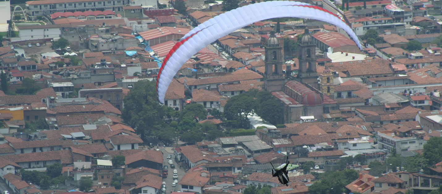 Parapente sobrevolando la parroquia de san Francisco en el centro de Valle de Bravo
